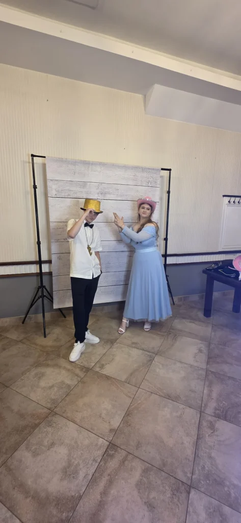 Uczestnicy balu pozujący przed jasnym tłem fotobudki